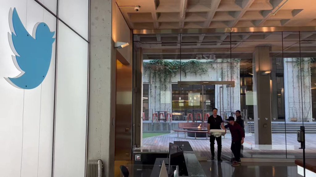 Elon Musk enters Twitter HQ carrying a sink, symbolizing the sweeping changes he brought to the platform after acquiring it, now rebranded as X.